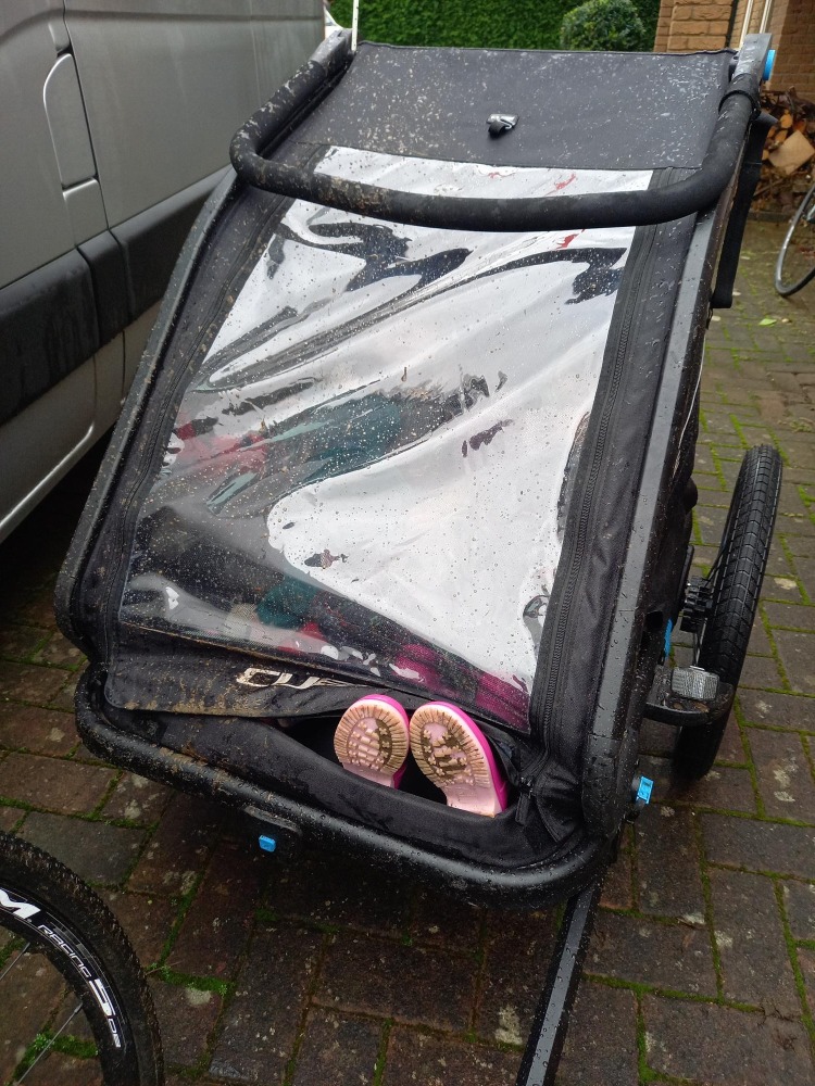 black cycle trailer with a pair of pink wellies sticking out