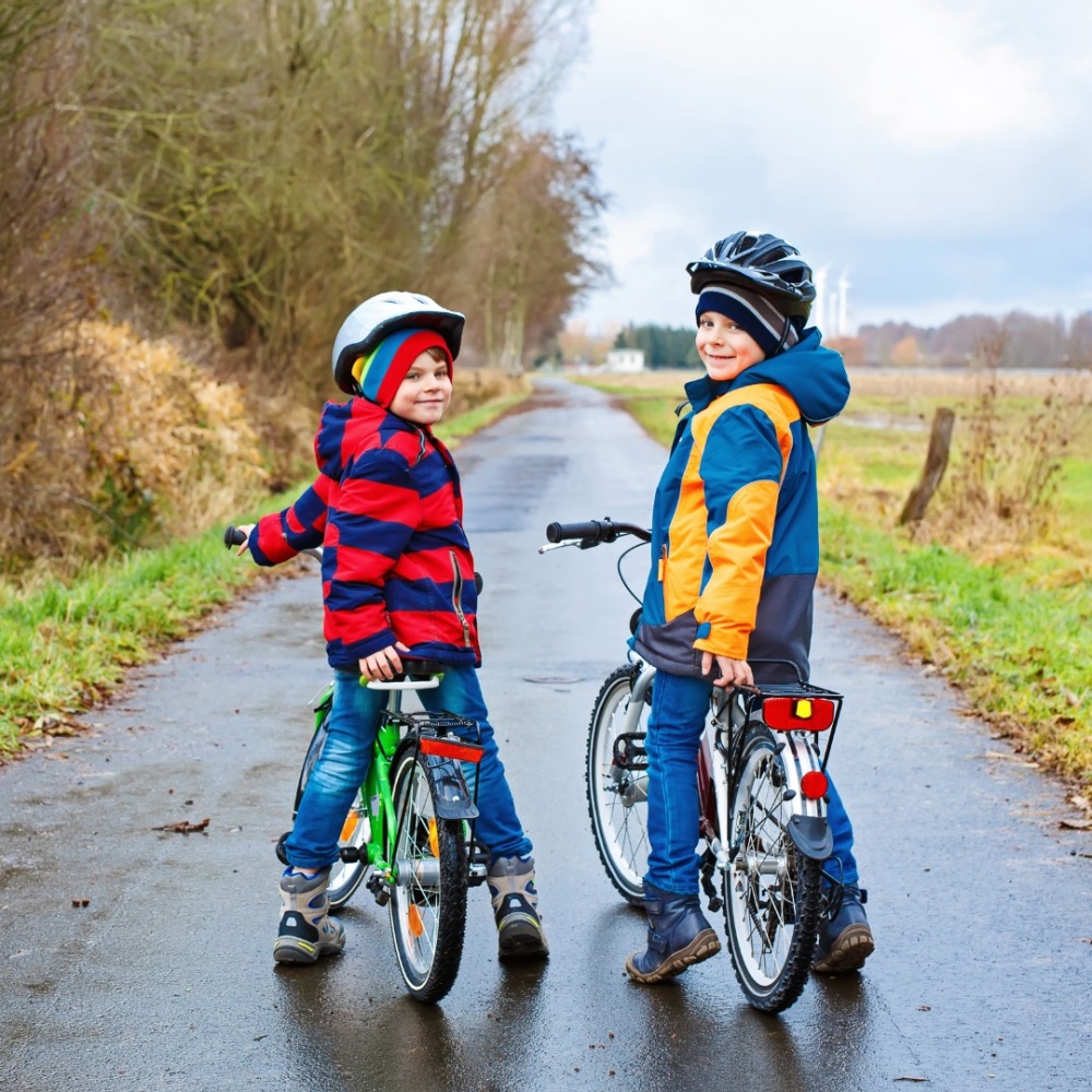 Winter cycling with kids: Two children standing over their bikes, turning back towards the camera