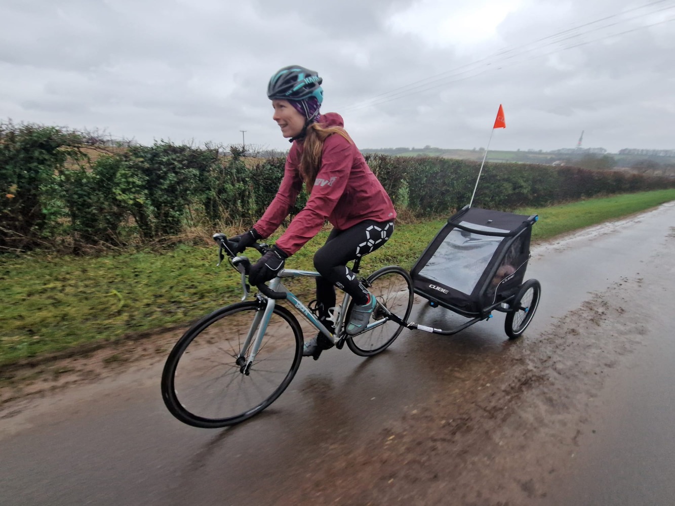 A woman riding a road bike with a trailer attached to the back