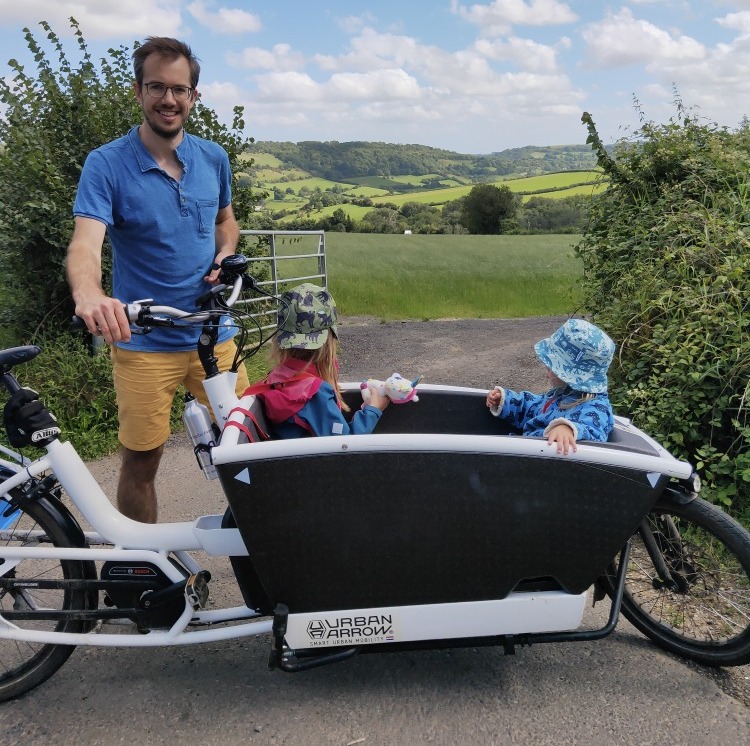 Dad holding Urban Arrow box bike with two children