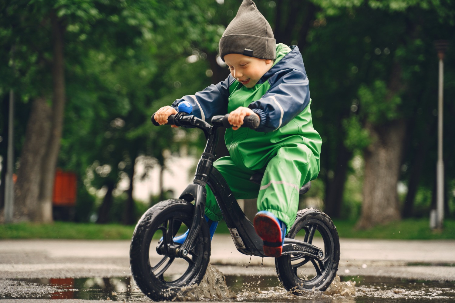 boy on a balance bike riding through a puddle