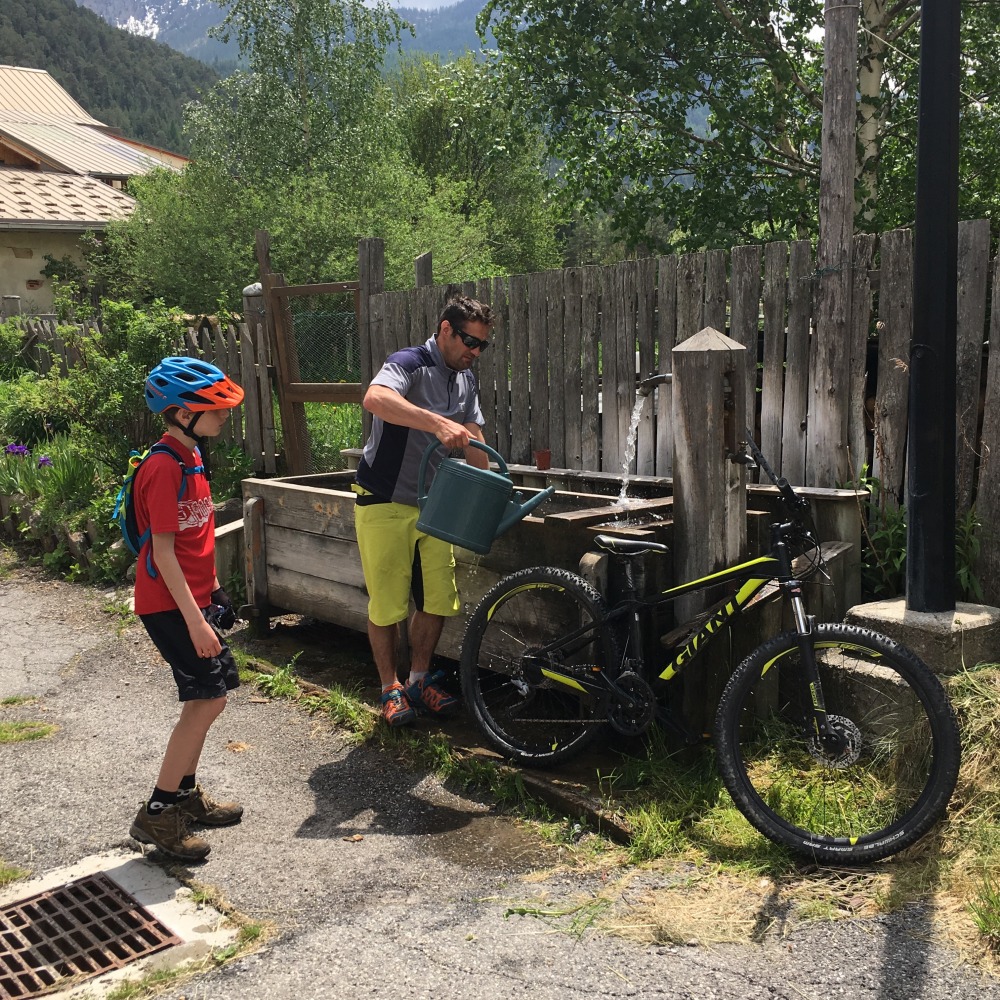 man and boy cleaning a bike with a watering can