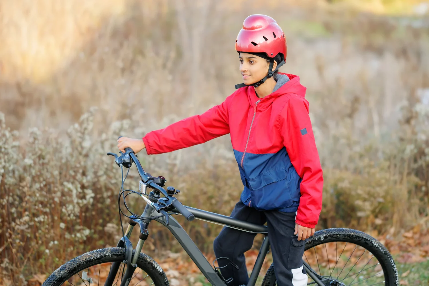 boy in a red jacket on a mountain bike wearing a red bold helmet