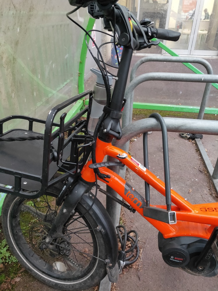 The front end of a long-tail cargo bike, locked to a sheffield stand