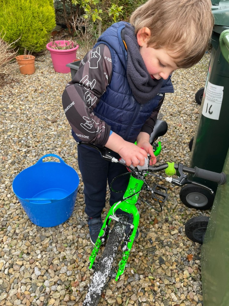 boy cleaning a green bike