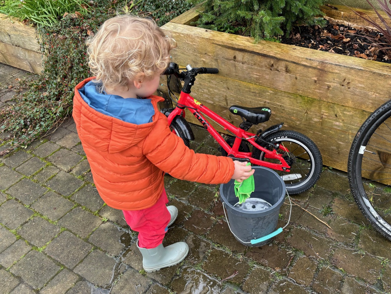Boy in a orange jacket cleaning his bike
