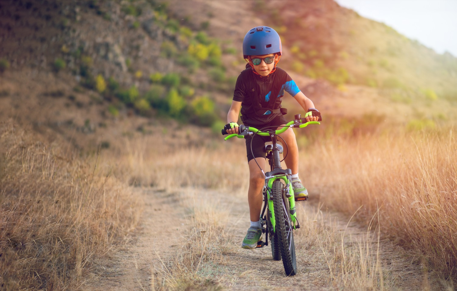 boy in a blue helmet riding a gravel trail
