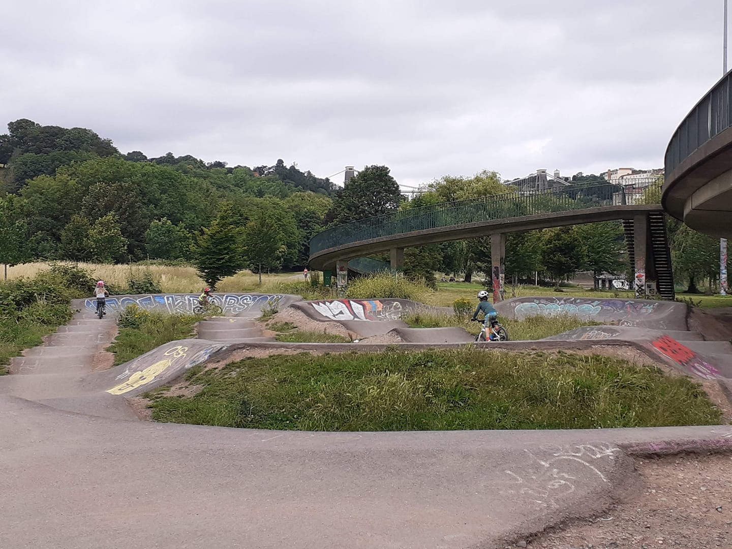 child riding a pump track with lots of graffiti