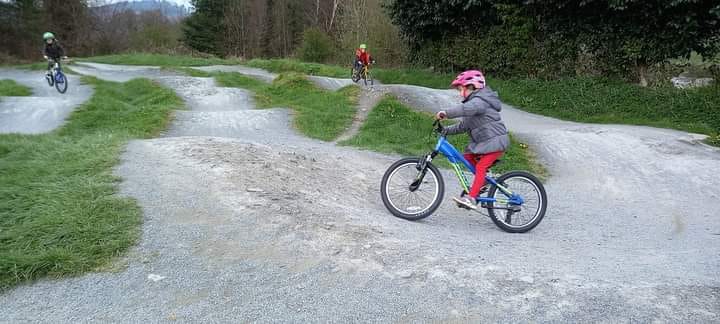child on a blue bike riding a pump track