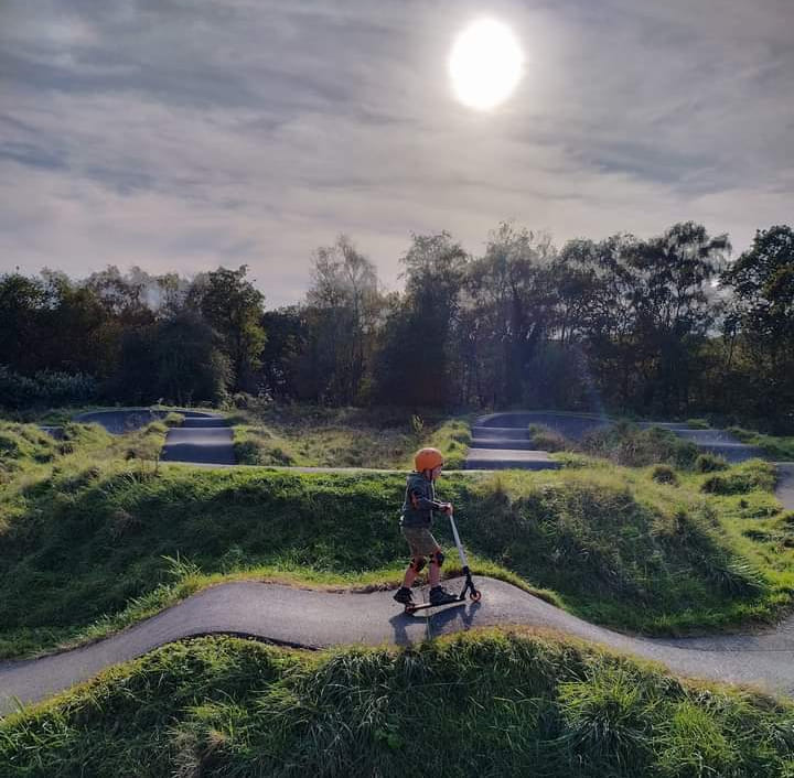 child riding a pump track on a scooter