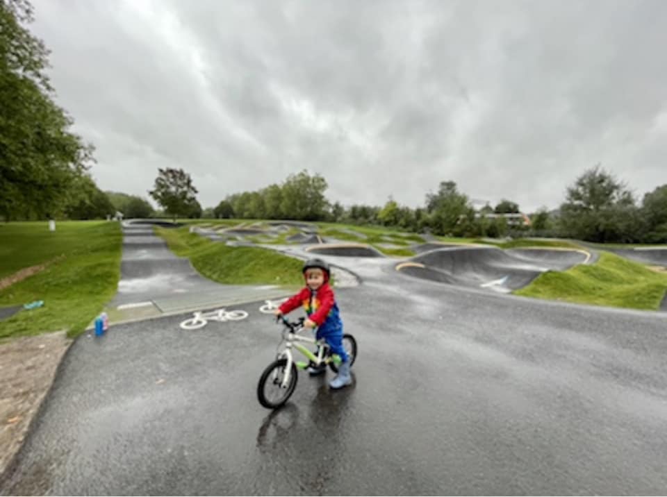 Child riding a pump track on a rainyday