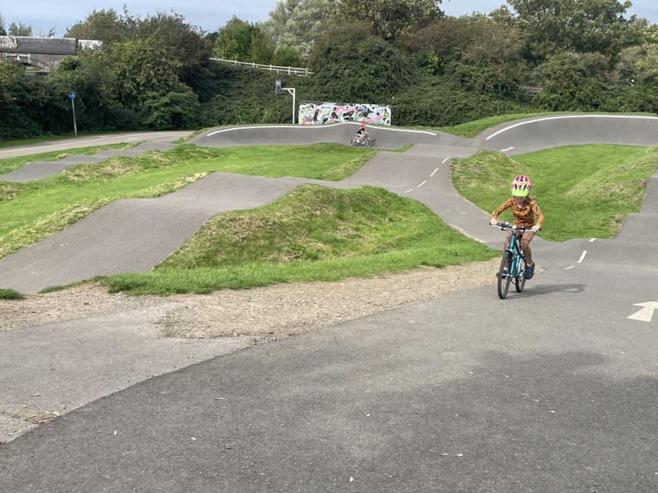 child riding a pump track on a sunny day