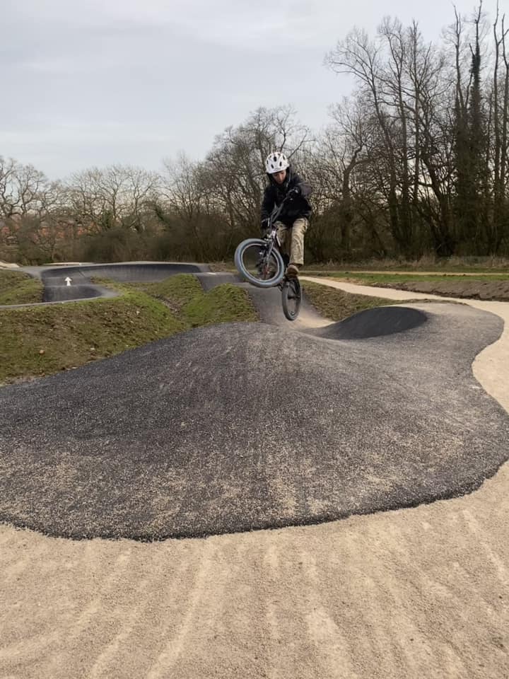 boy doing a jump at a pump track