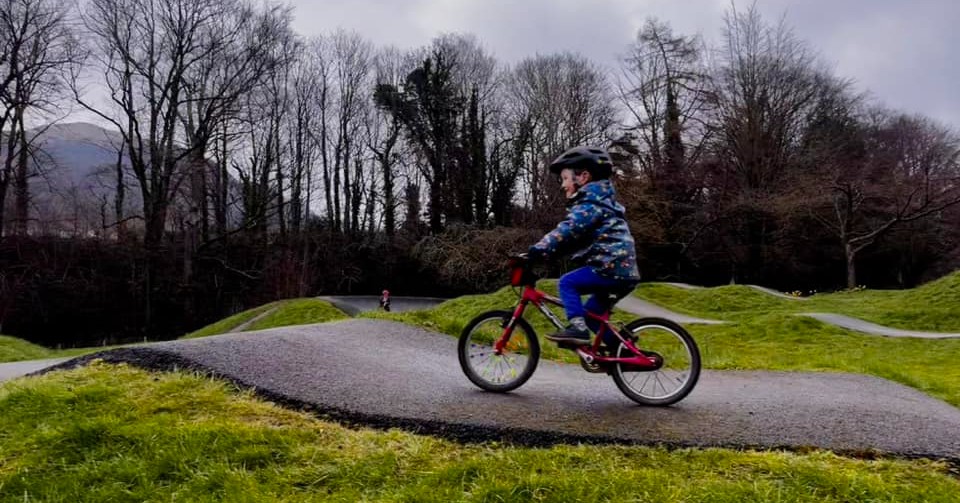 boy on a red bike riding a pump track