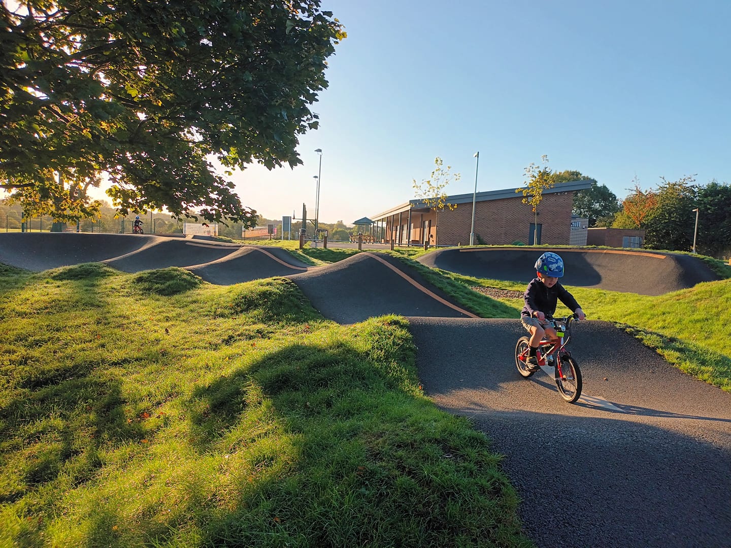 child on an orange bike riding a pump track