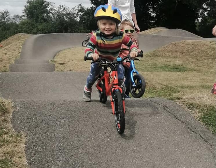 little boy on an orange bike at a pump track