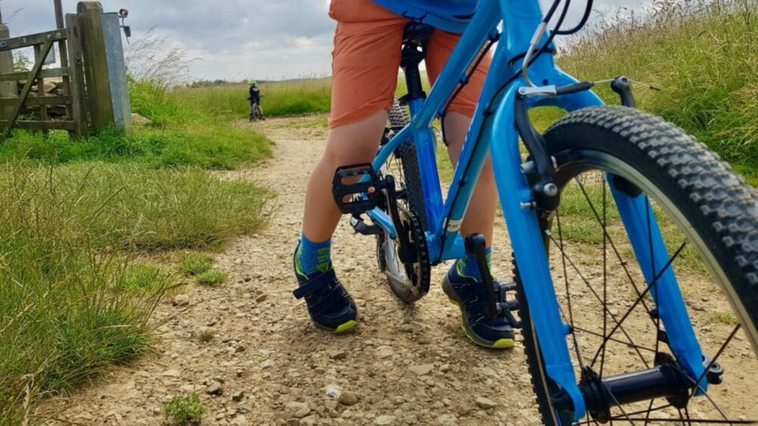 A close up view of a child's legs mounted over a blue bike