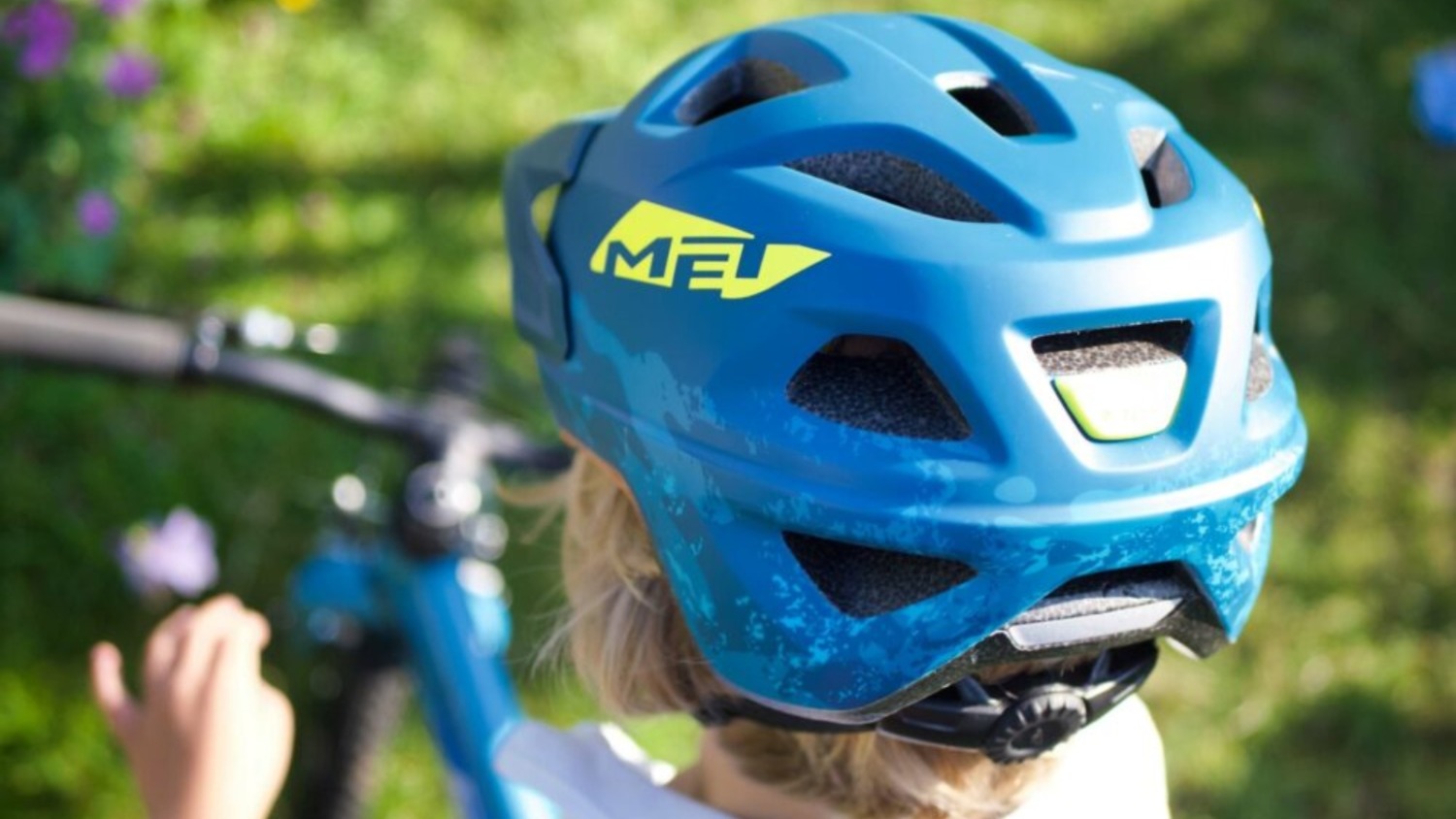 A close up view from behind of a child wearing a blue Met helmet