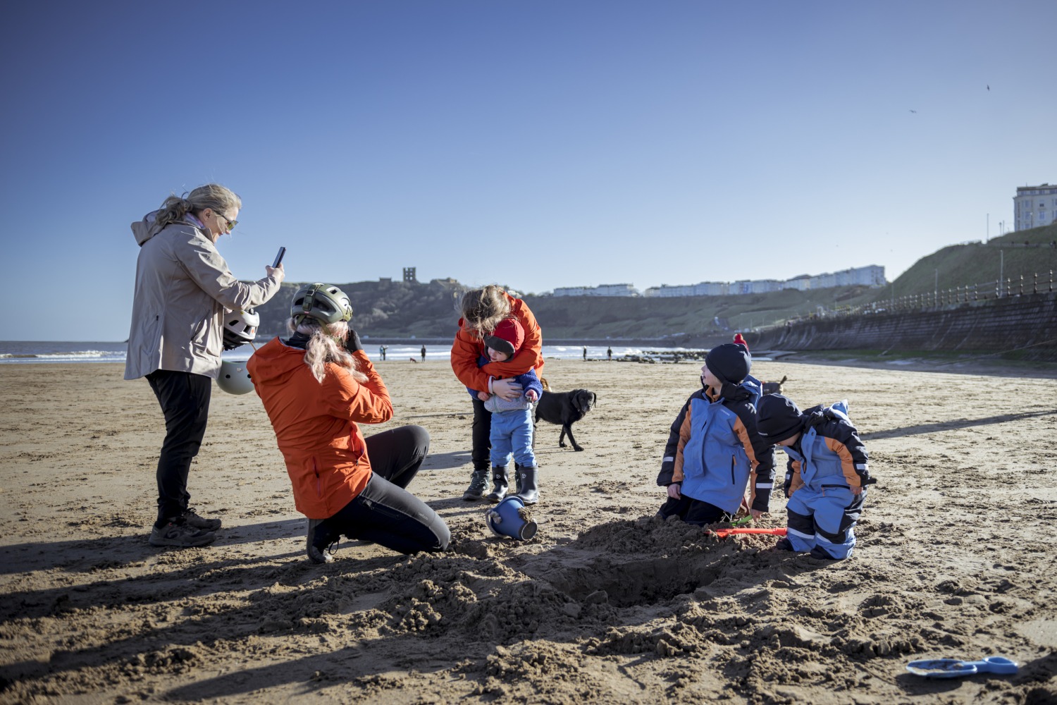 4 cyclists building sandcastles on the beach on a sunny day