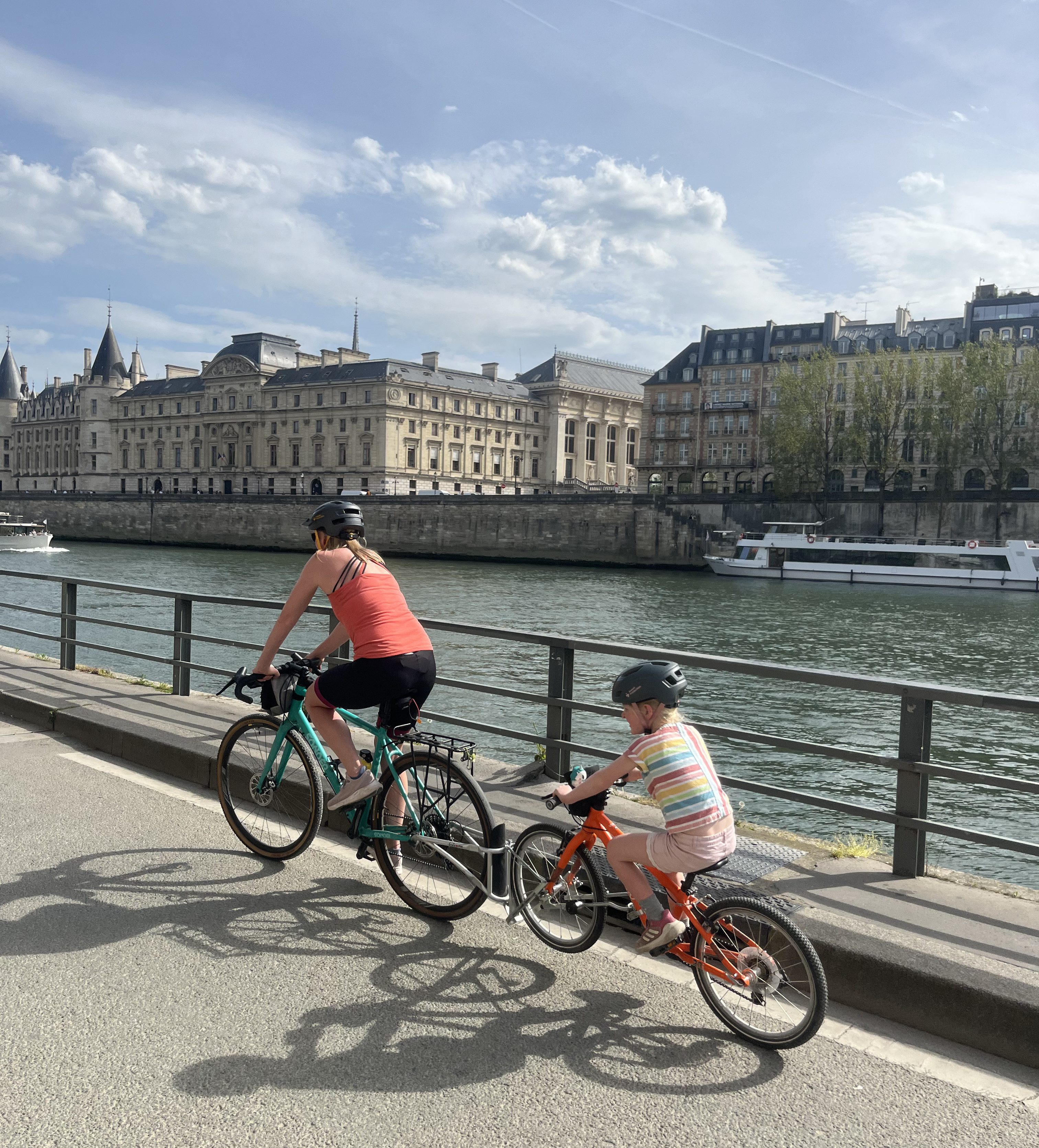 Yomo 20 kids bike being used by a young girl attached to a FollowMe tandem onto an adults bike - riding along the rive seine 