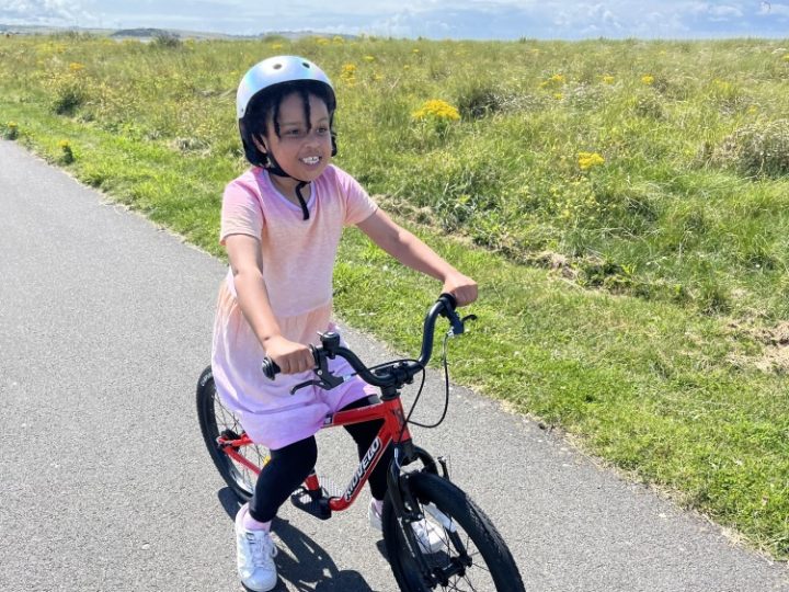 a girl in a pink dress riding her kidvelo rookie 18 bike