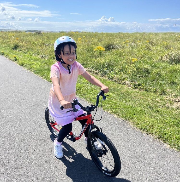 a black girl in a pink dress riding her kidvelo rookie 18 bike