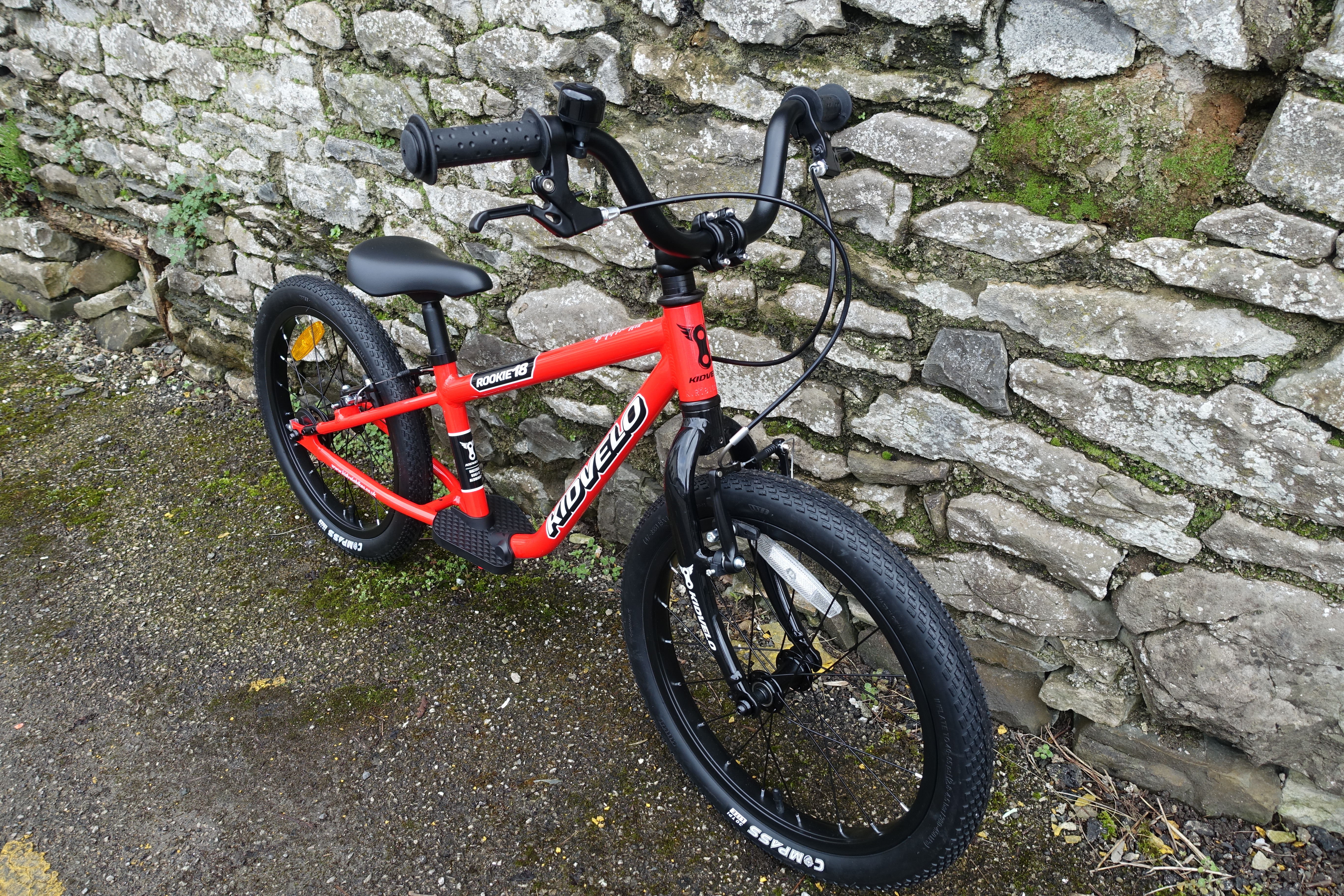 Kidvelo Rookie 18 kids bike in red resting against a stone wall