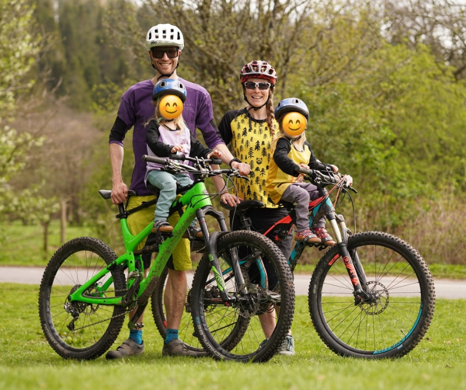 The family who are doing the Kidvelo Rookie 14 review, in a family photo of two parents on their mountain bikes with their twin daughters on shotgun seats