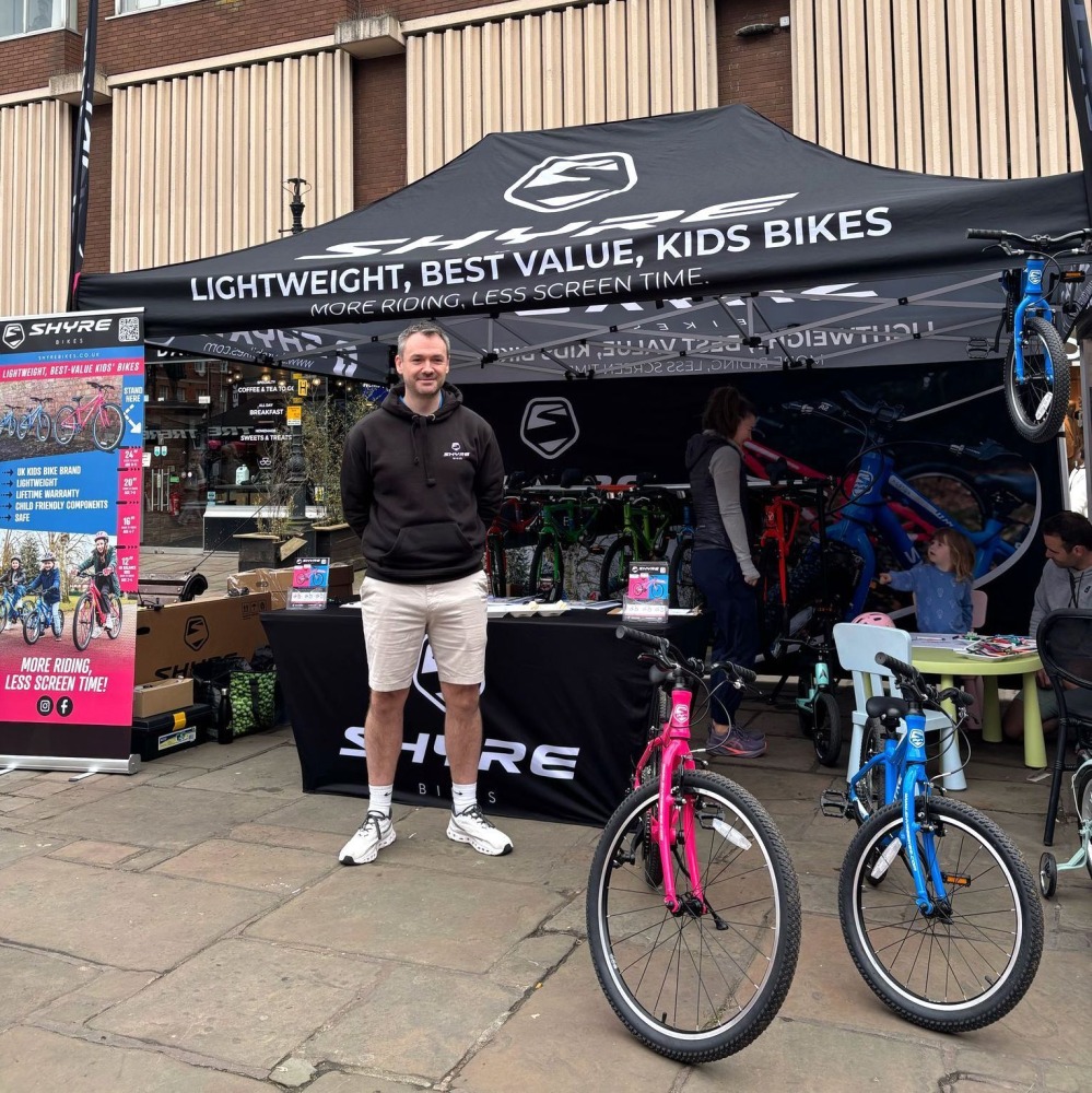 Kev from Shyre Bikes standing in front of a gazebo with two Shyre bikes next to him