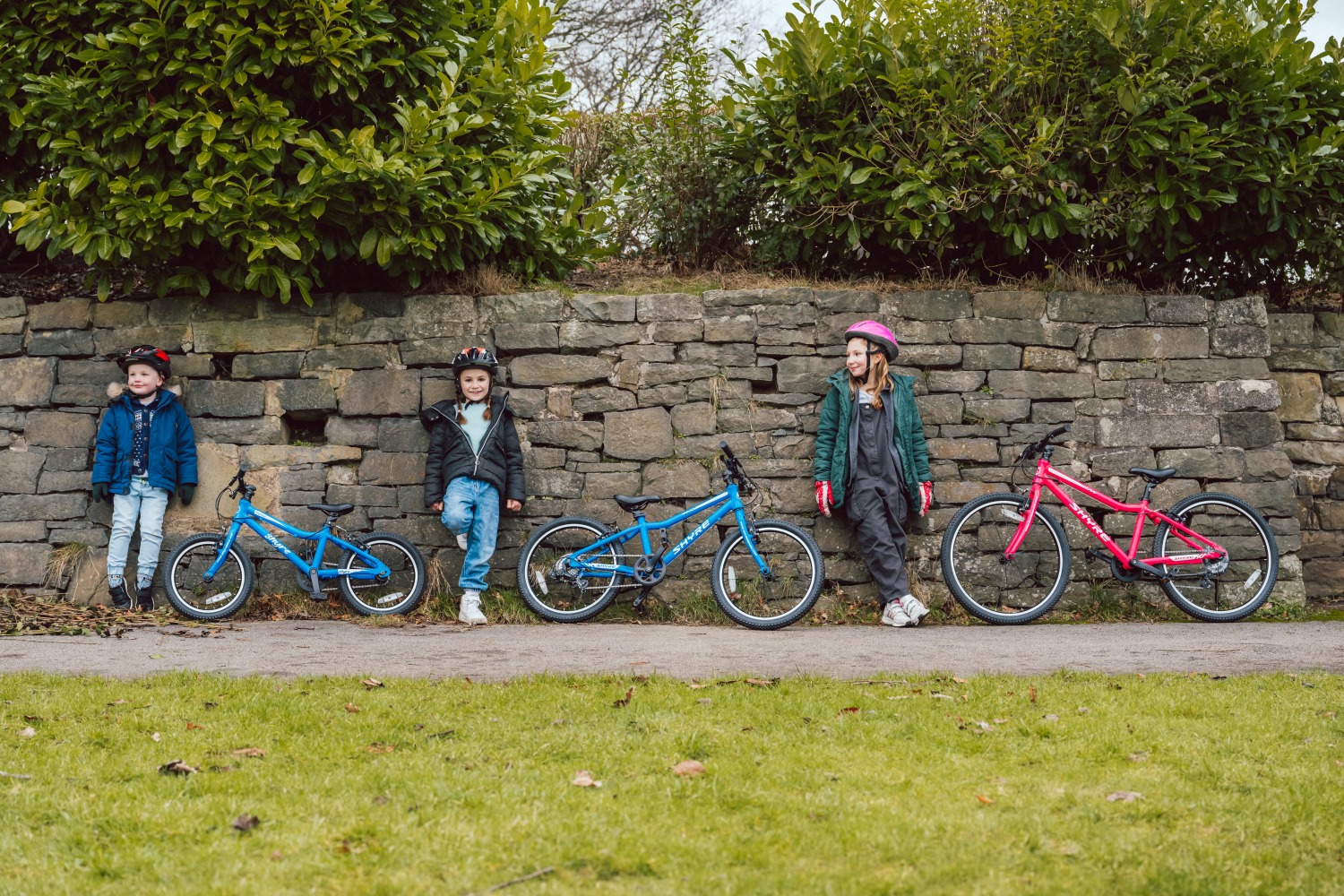 Adam LV Photography_ Shyre bikes Shoot-70 Three kids leaning against a brick wall, with their shyre bikes next to them