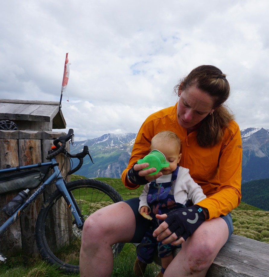 Copy of DSC02172 Hetty Kingston sat on a bench with her bike propped up next to her, and a toddler on her lap, who she's helping to drink from a sippy cup