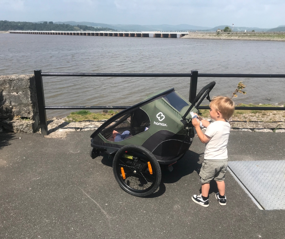 a little boy pushing the Hamax Outback trailer by the sea side