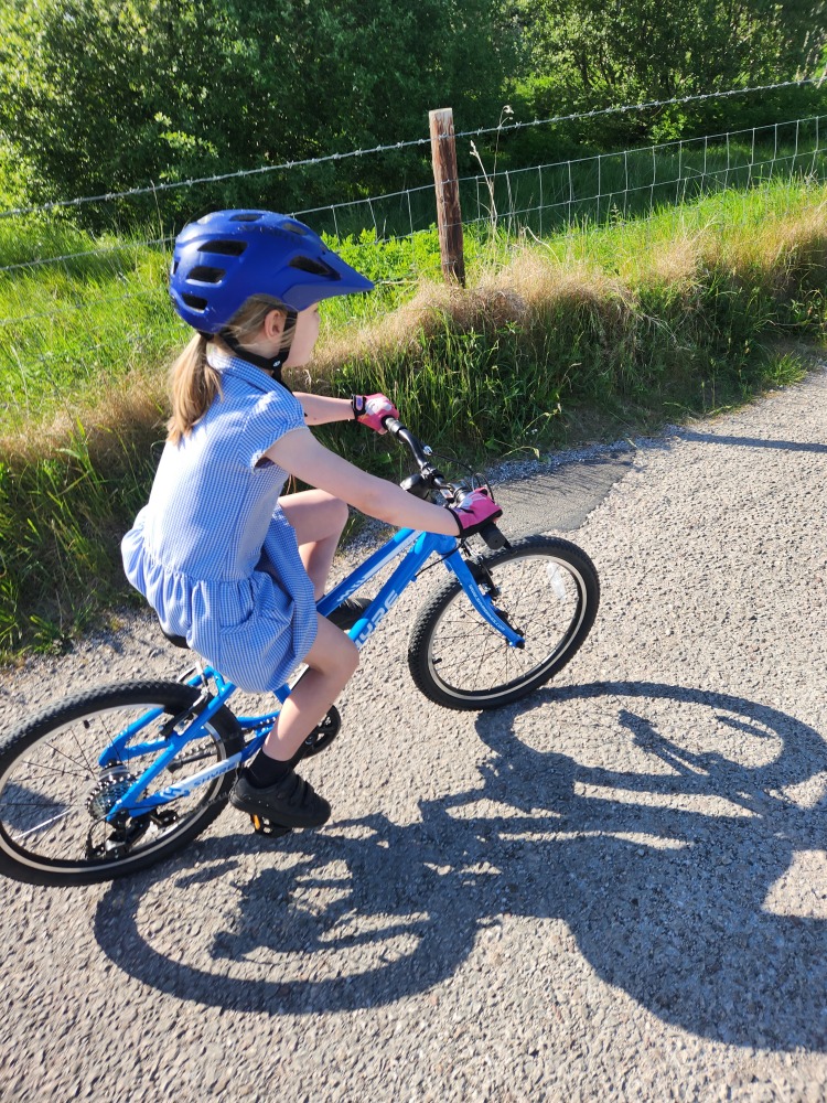 Shyre Hopton 20 review: A little girl in a school dress cycling the Shyre bike along a tarmac path
