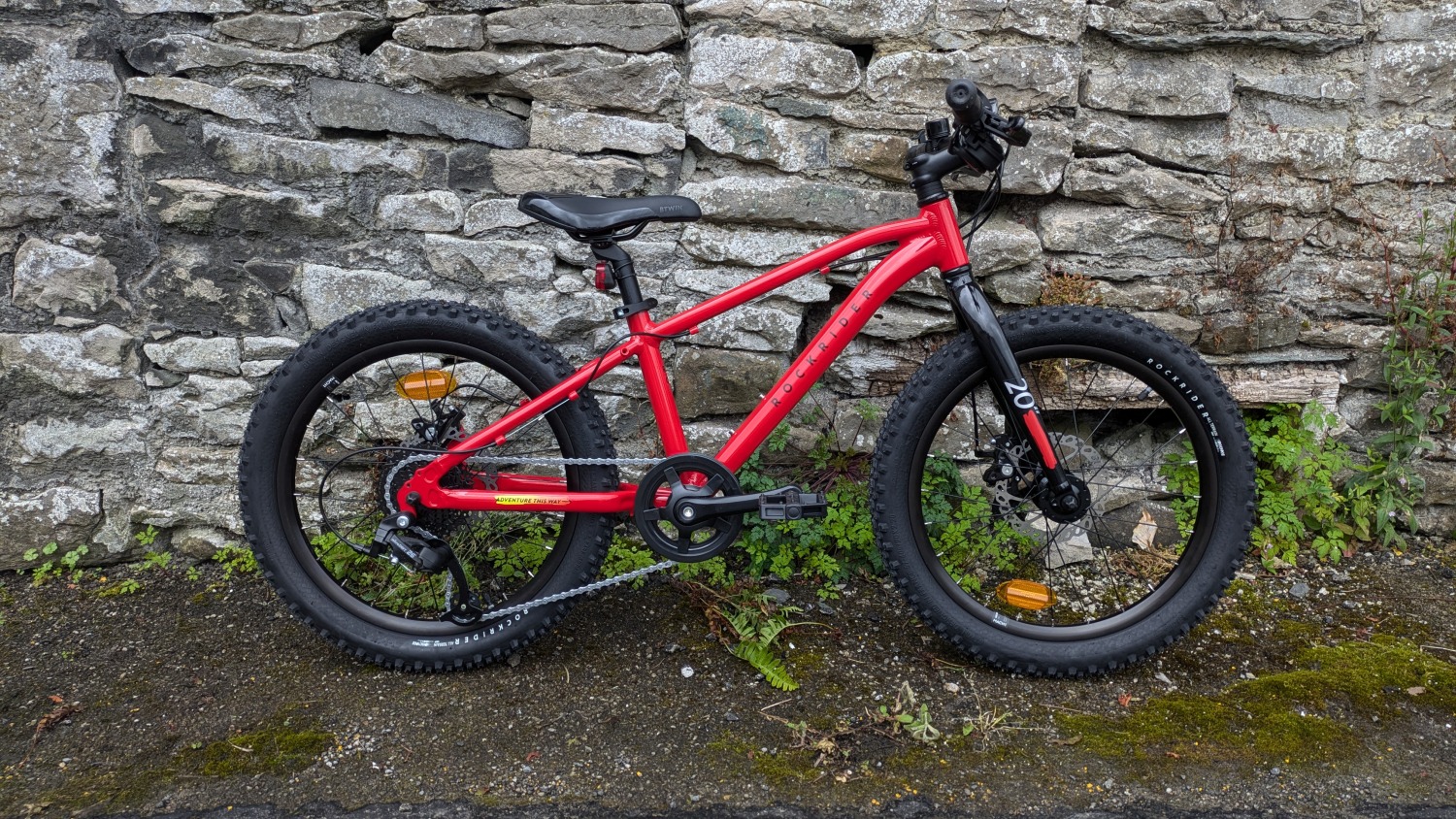 Red 20 inch BTWIN EXPL 900r kids mountain bike leant against a wall