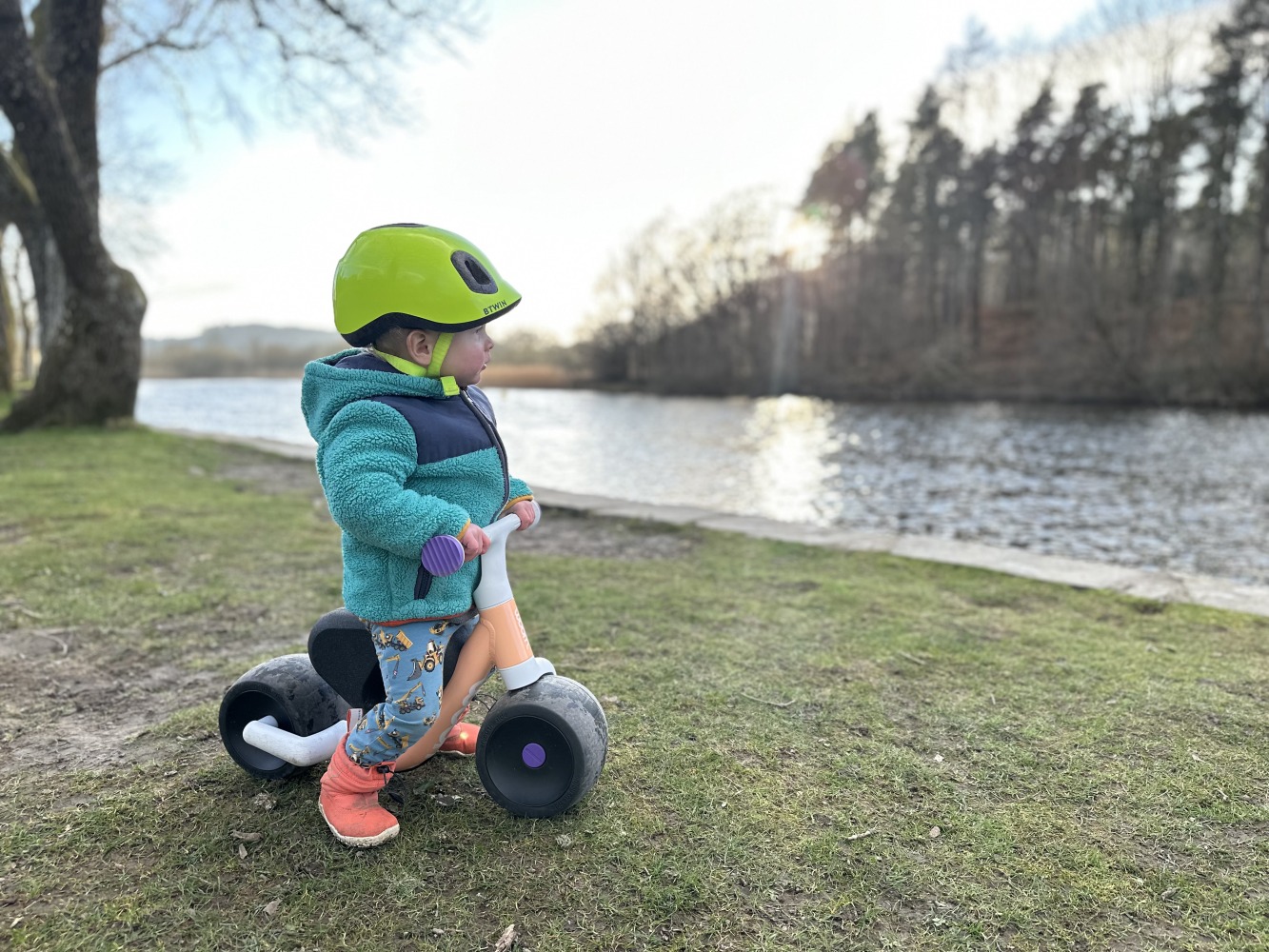 woom WOW side on view of a toddler riding the bike beside some water