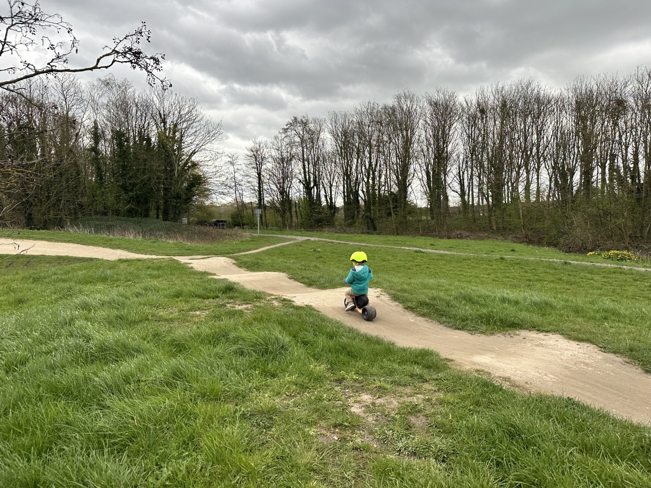 woom WOW toddler balance bike being ridden on a dirt path in a park