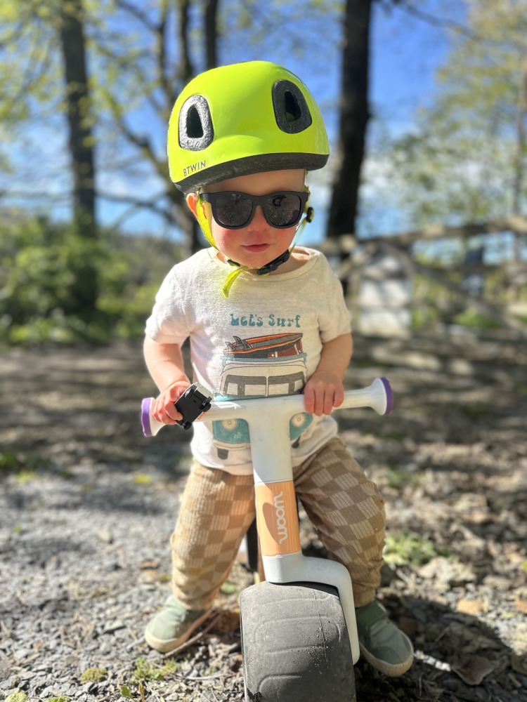 Toddler bike reviewer riding the woom WOW balance bike in the sunshine
