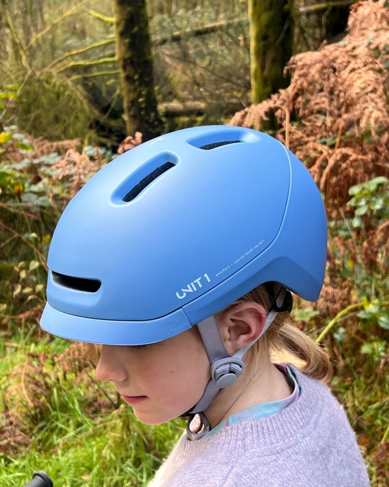 A girl wearing a blue SPARKY helmet- riding her orange mountain bike