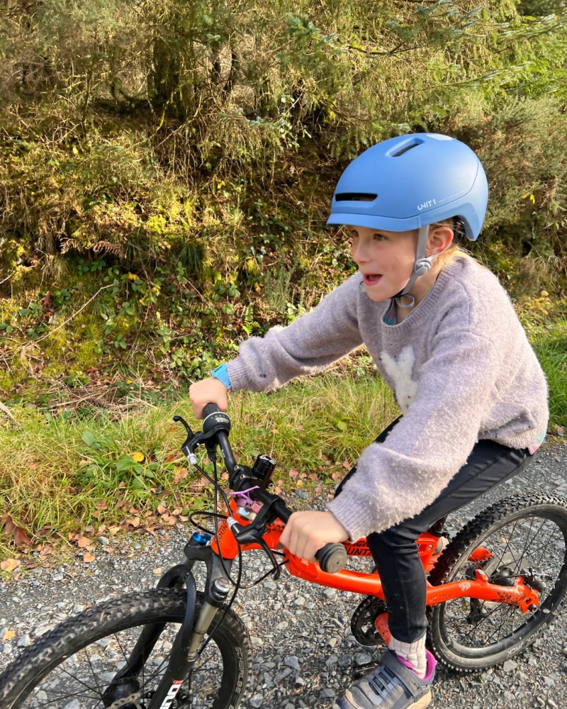 A girl wearing a blue SPARKY helmet- riding her orange mountain bike