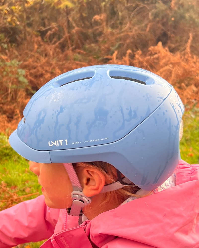 A girl wearing a blue SPARKY helmet and a pink coat