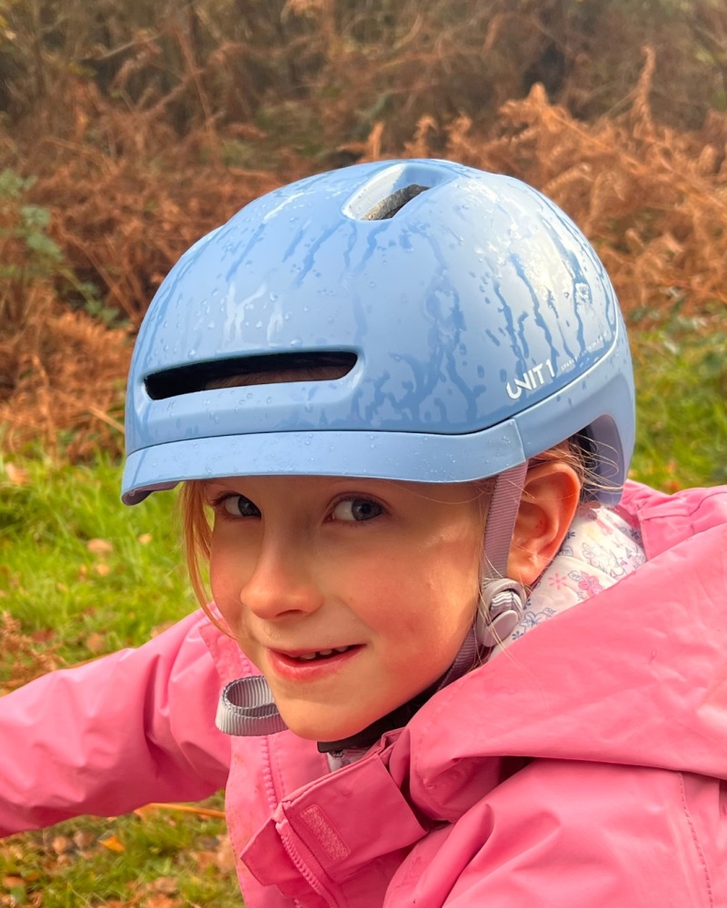 A girl wearing a blue SPARKY helmet and a pink coat