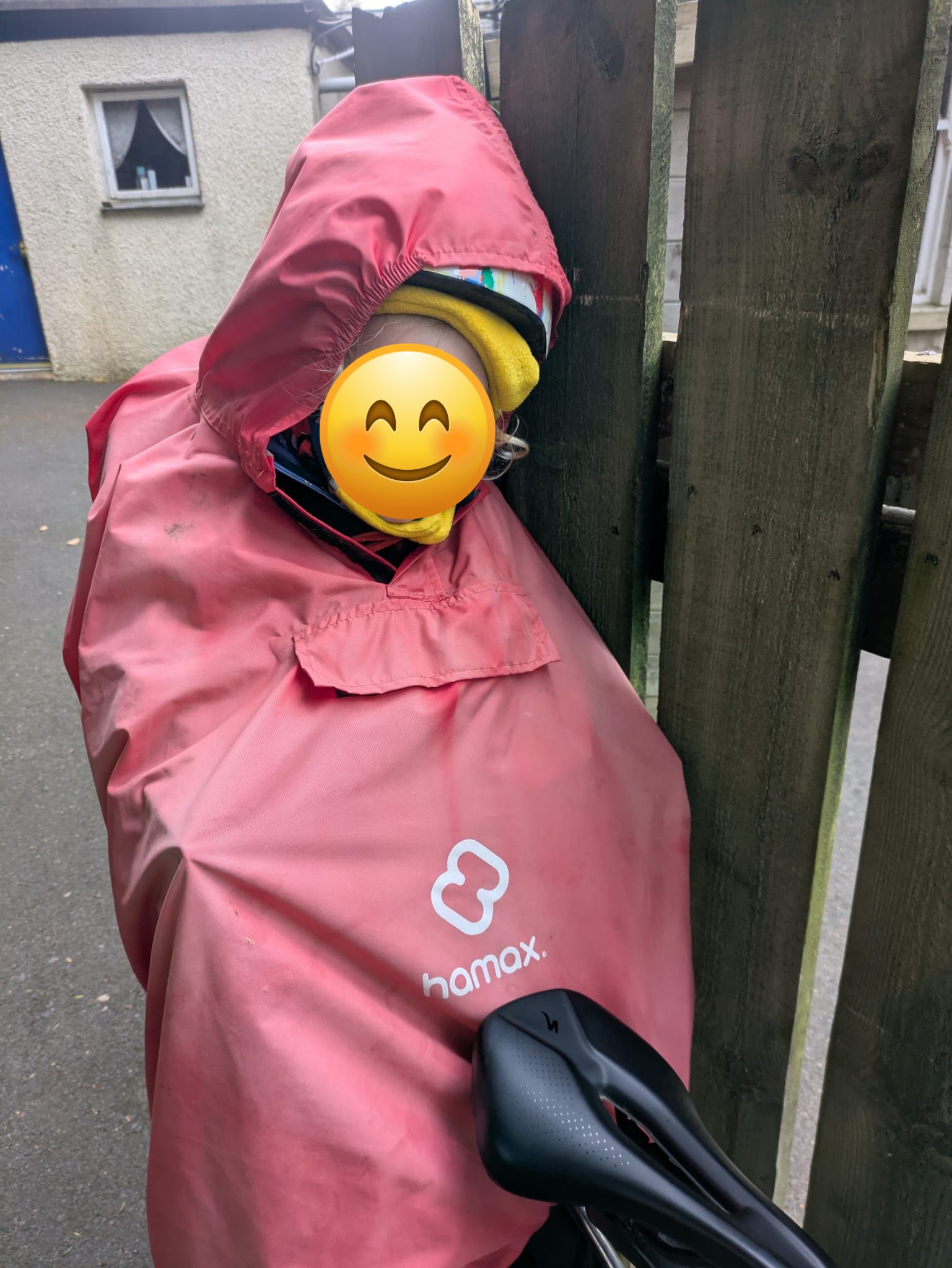 a little boy on a rear bike seat in his red Hamax Bike Seat Rain Poncho