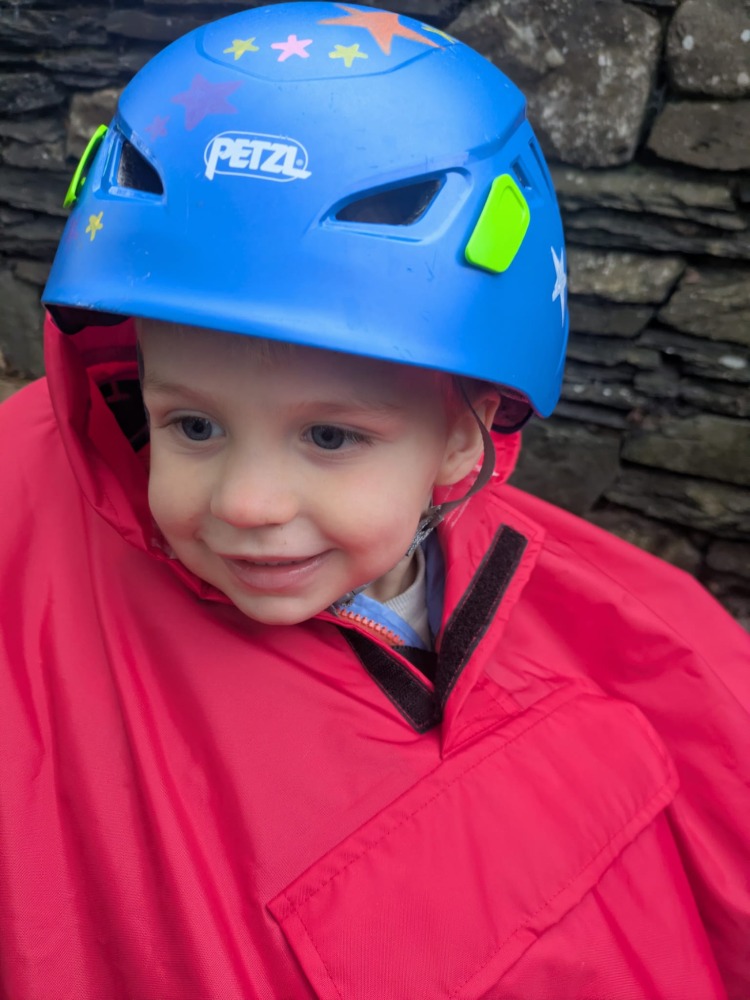 a little boy on a rear bike seat in his red Hamax Bike Seat Rain Poncho