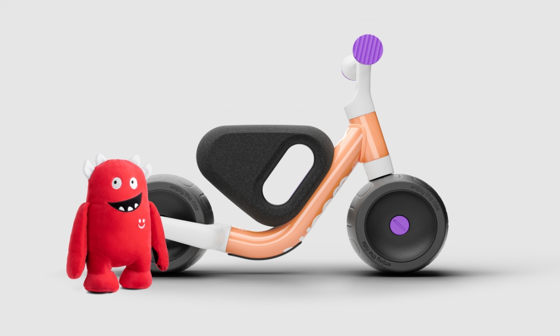 Best bikes for a 1 year old: the woom WOW ride-on seen from the side with the Buddy soft toy standing next to it
