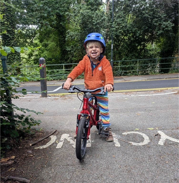 Young boy smiling while riding the Hornit HERO 14 kids bike in red 