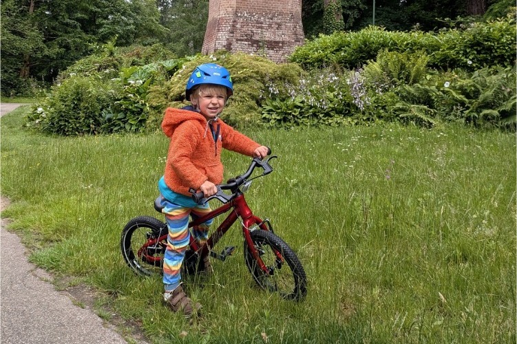 Hornit HERO 14 kids bike being ridden on grass beside a paved path 