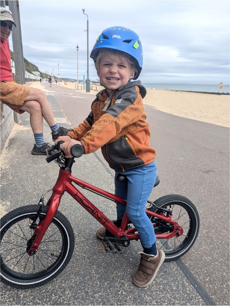 A young boy riding the Hornit HERO 14 kids bike in red