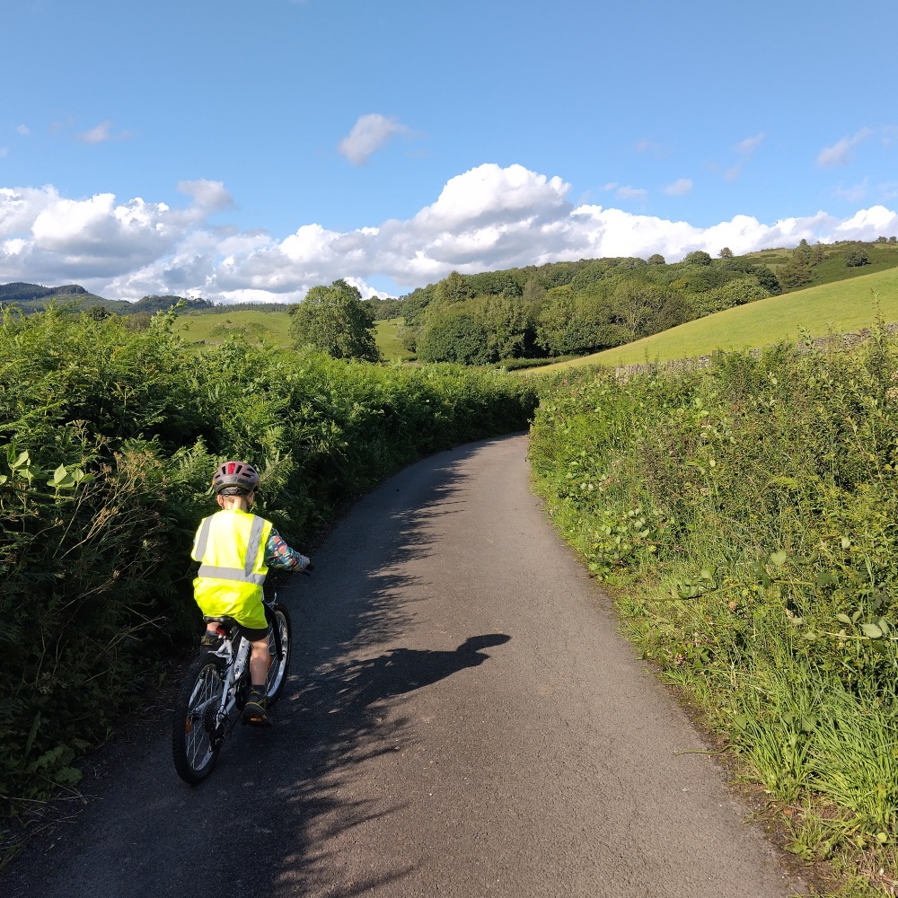 Boy in hi-vis riding the Rockrider 20" 120 Expl MTB along a country road on a sunny day