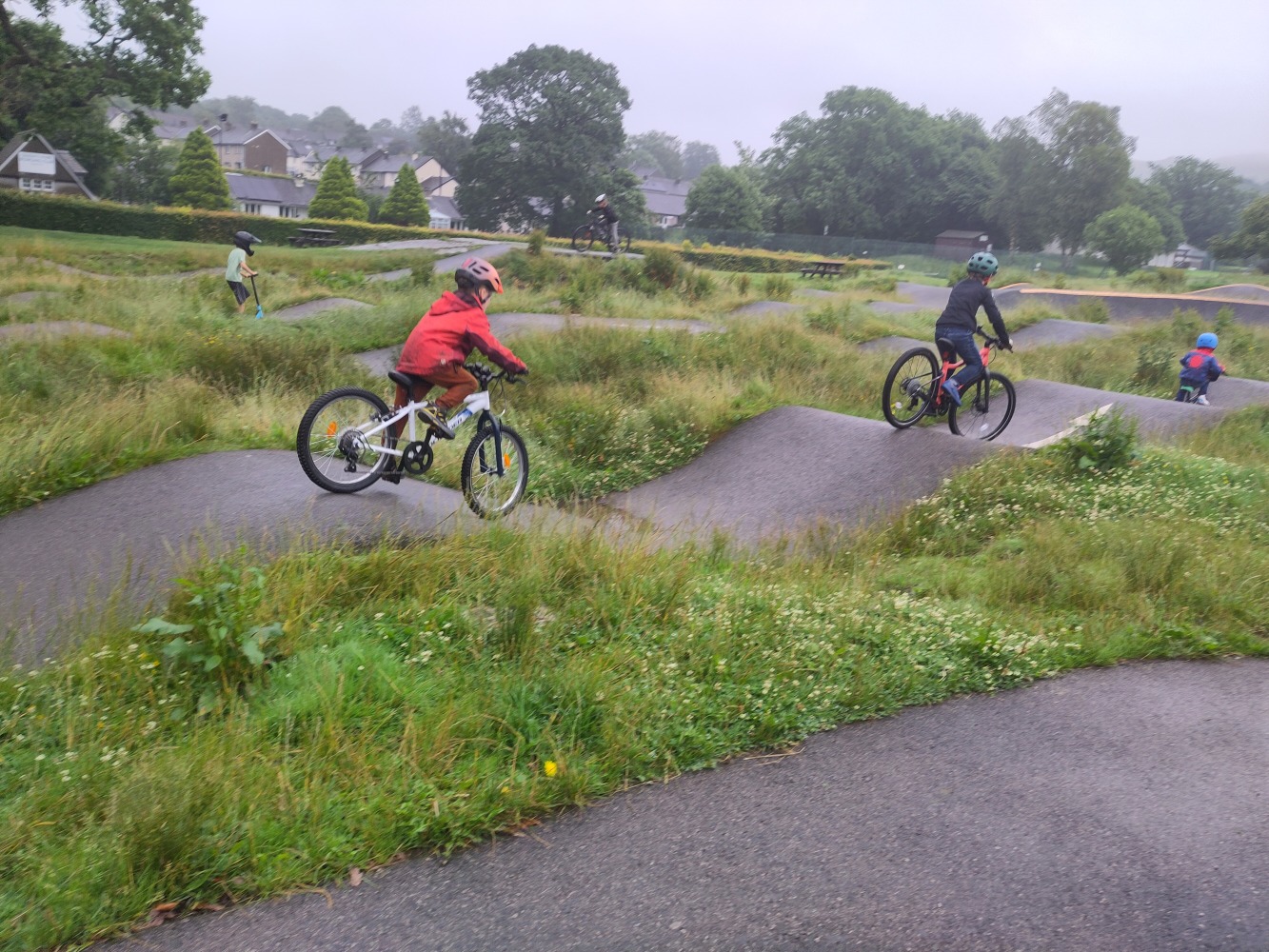 Child with a red coat riding the Rockrider 20" MTB Expl 120 on a pump track 