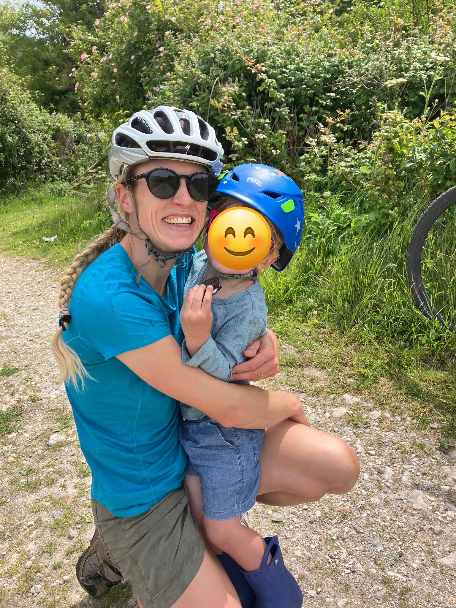 a woman holding her son both wearing bike helmets out on a family cycling day